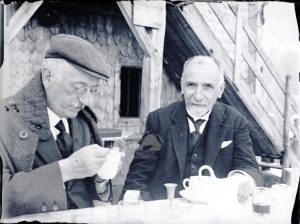 Due signori fanno colazione seduti davanti ad una baita di montagna, Anni '20
