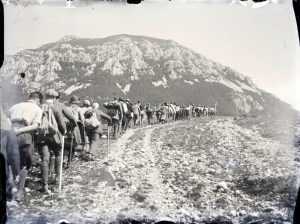 Escursionisti in fila indiana lungo un sentiero fra le montagne, Anni '20