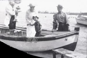 Babbo, mamma e due figlie in partenza per una gita in barca. Tutti in posa, compreso il barcaiolo. Anni '20