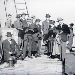 Eleganti signori e una signora, tutti con cappello, in posa per una foto sulla tolda di una nave prima dell'approdo. Siamo circa negli Anni '20