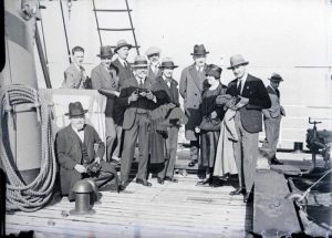 Eleganti signori e una signora, tutti con cappello, in posa per una foto sulla tolda di una nave prima dell'approdo. Siamo circa negli Anni '20