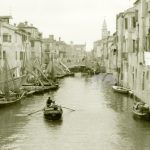 Una piccola imbarcazione a remi attraversa il Canal Vena a Chioggia fra le barche ormeggiate. Siamo negli Anni '50 circa