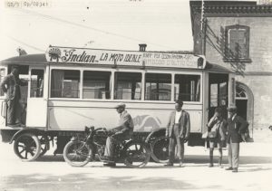 Il tram davanti alla stazione ferroviaria di Cesena in attesa di partire verso il centro della città. I passeggeri scrutano con attenzione una moto "Indian" che proprio l'autocorriera pubblicizza. Siamo nel 1925