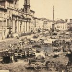 Una bellissima piazza Navona a Roma, in un giorno di mercato, affollatissima di carri bancarelle e persone. Siamo intorno al 1885