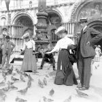 Due giovani signore danno il cibo ai piccioni in Piazza San Marco a Venezia circa nel 194-1905