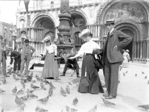 Due giovani signore danno il cibo ai piccioni in Piazza San Marco a Venezia circa nel 194-1905